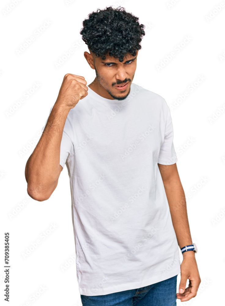 Young arab man wearing casual white t shirt angry and mad raising fist frustrated and furious while shouting with anger. rage and aggressive concept. Young arab man wearing casual white t shirt angry and mad raising fist frustrated and furious while shouting with anger. rage and aggressive concept.