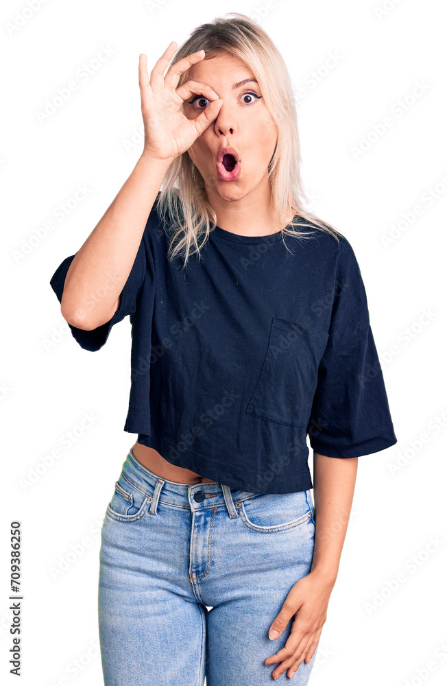 Young beautiful blonde woman wearing casual t-shirt doing ok gesture shocked with surprised face, eye looking through fingers. unbelieving expression. Young beautiful blonde woman wearing casual t-shirt doing ok gesture shocked with surprised face, eye looking through fingers. unbelieving expression.