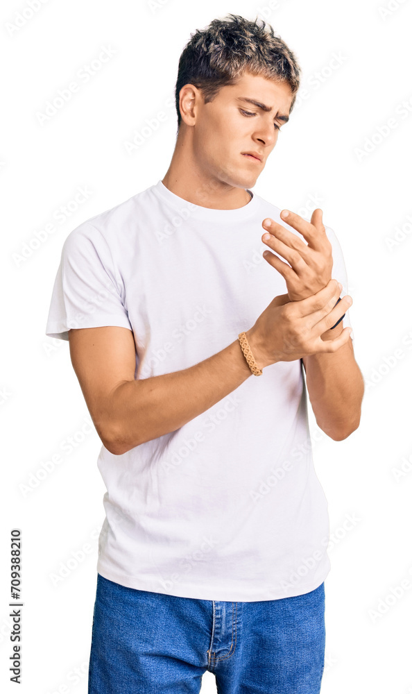 Young handsome man wearing casual white tshirt suffering pain on hands and fingers, arthritis inflammation Young handsome man wearing casual white tshirt suffering pain on hands and fingers, arthritis inflammation