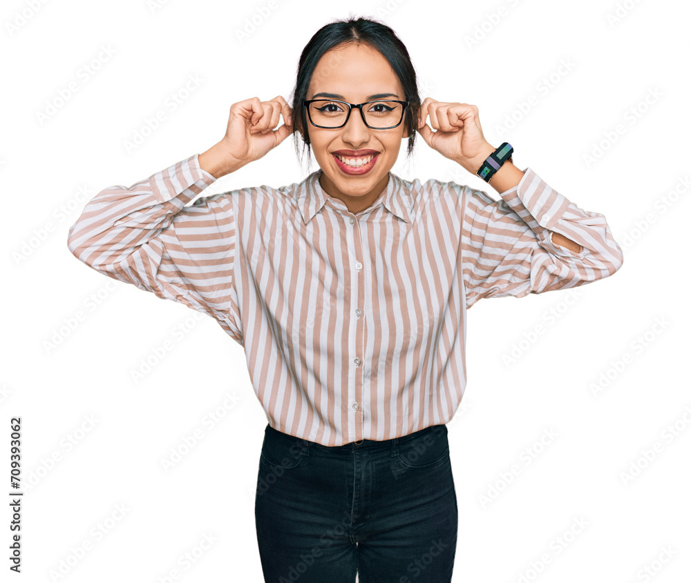 Young hispanic girl wearing casual clothes and glasses smiling pulling ears with fingers, funny gesture. audition problem Young hispanic girl wearing casual clothes and glasses smiling pulling ears with fingers, funny gesture. audition problem