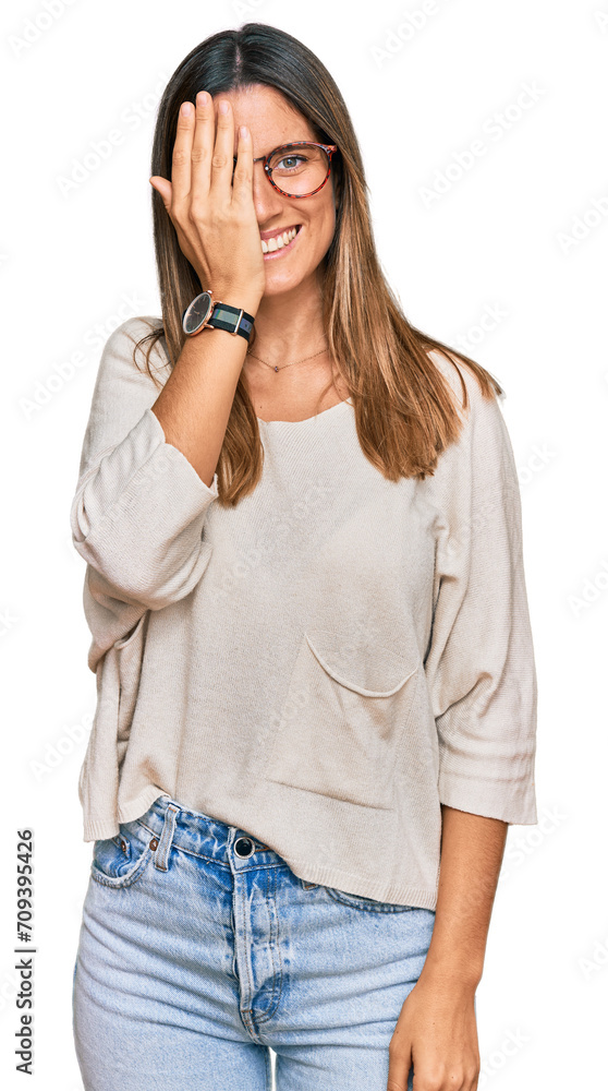 Young woman wearing casual clothes and glasses covering one eye with hand, confident smile on face and surprise emotion. Young woman wearing casual clothes and glasses covering one eye with hand, confident smile on face and surprise emotion.