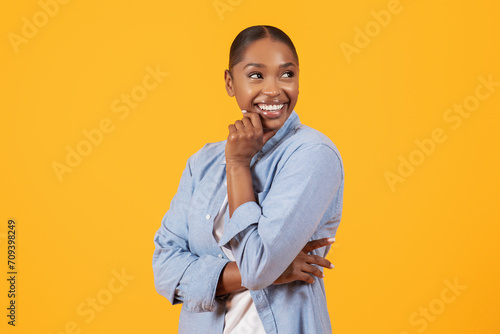 Black woman in denim shirt touching chin looking aside, studio