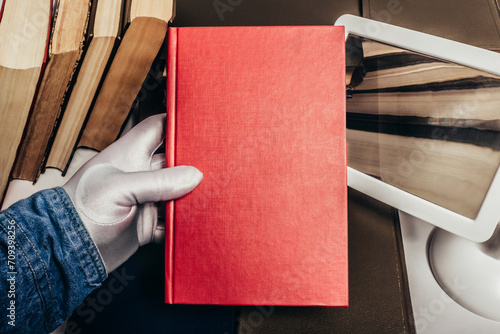 Photo of antiquarian male person in white gloves holding a red book in their hand. photo