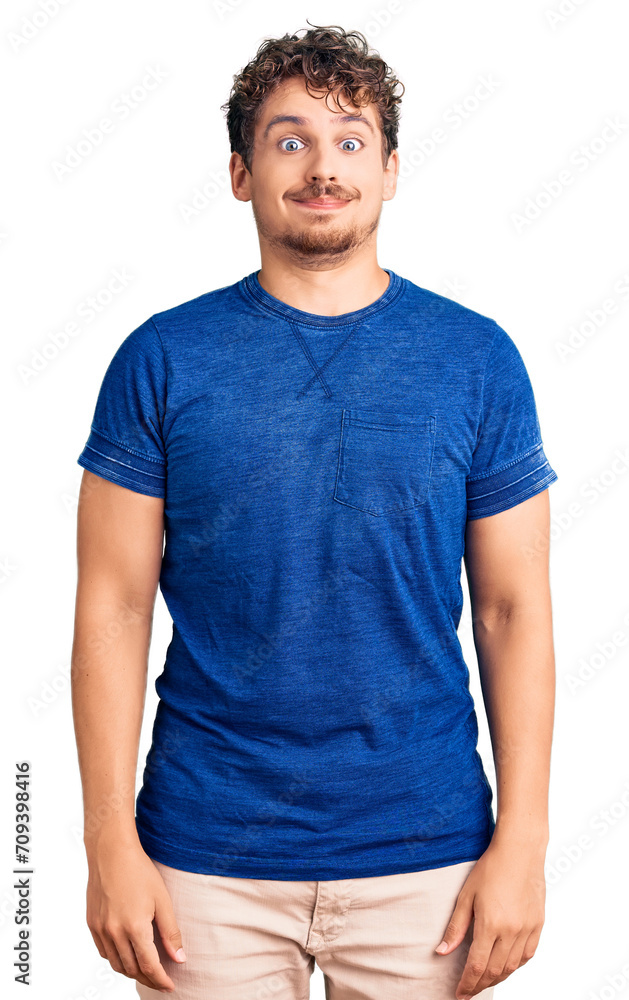 Young handsome man with curly hair wearing casual clothes puffing cheeks with funny face. mouth inflated with air, crazy expression. Young handsome man with curly hair wearing casual clothes puffing cheeks with funny face. mouth inflated with air, crazy expression.