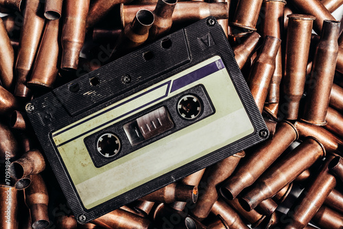 Photo of an old black colored blank retro audio tape cassette on pile of bullets.