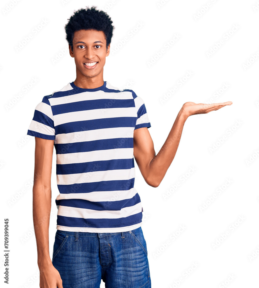 Young african american man wearing casual clothes smiling cheerful presenting and pointing with palm of hand looking at the camera.