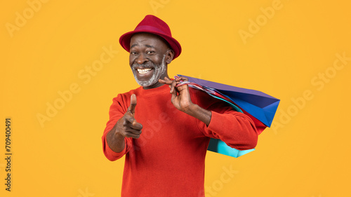 Charismatic black senior with a warm smile, wearing a red sweater and hat, playfully winking