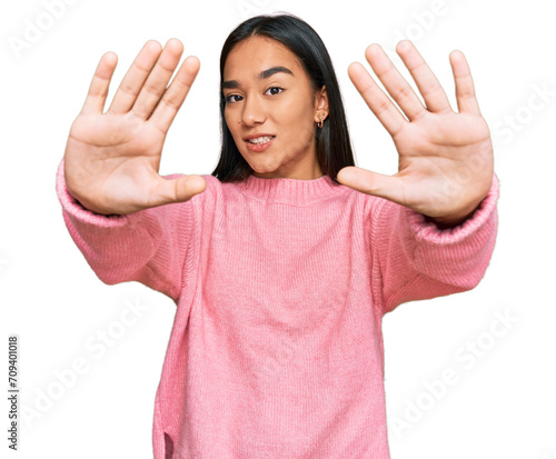 Young asian woman wearing casual winter sweater doing frame using hands palms and fingers, camera perspective