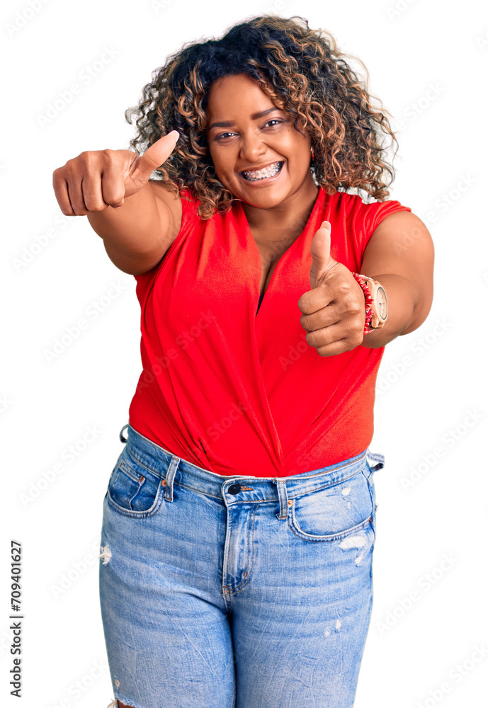 Young african american plus size woman wearing casual style with sleeveless shirt approving doing positive gesture with hand, thumbs up smiling and happy for success. winner gesture. Young african american plus size woman wearing casual style with sleeveless shirt approving doing positive gesture with hand, thumbs up smiling and happy for success. winner gesture.