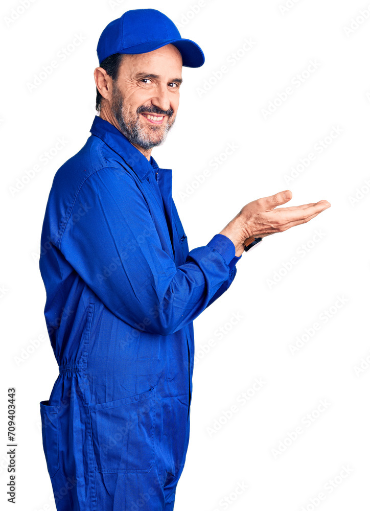 Middle age handsome man wearing mechanic uniform pointing aside with hands open palms showing copy space, presenting advertisement smiling excited happy