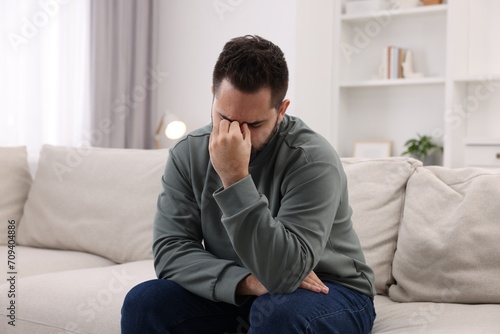 Man suffering from headache on sofa at home © New Africa