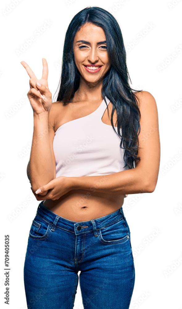 Beautiful hispanic woman wearing casual clothes smiling with happy face winking at the camera doing victory sign with fingers. number two. Beautiful hispanic woman wearing casual clothes smiling with happy face winking at the camera doing victory sign with fingers. number two.