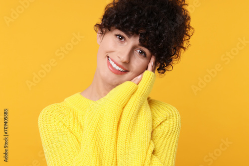 Happy young woman in stylish warm sweater on yellow background