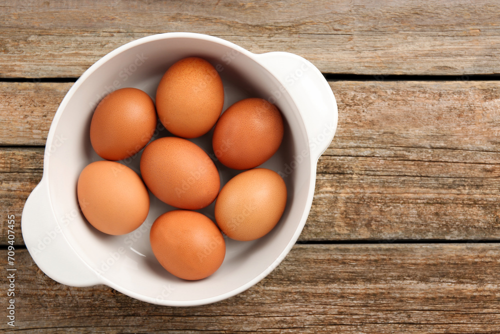 Unpeeled boiled eggs in saucepan on old wooden table, top view. Space for text Unpeeled boiled eggs in saucepan on old wooden table, top view. Space for text