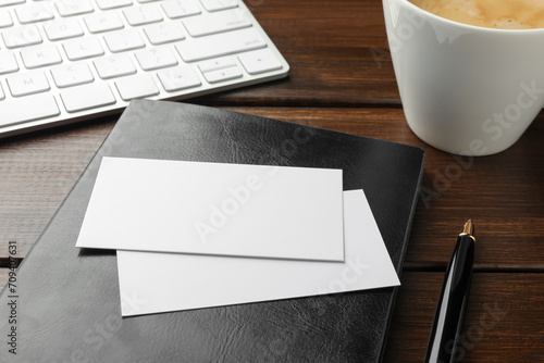Blank business cards  notebook and pen on wooden table  closeup. Mockup for design