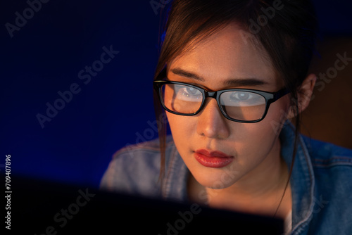 Portrait young beautiful Asian creative with glasses of serious face looking on pc to search project creator social media online, planning strategy creator at neon modern office at night. Stratagem.