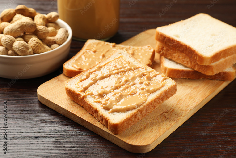 Delicious toasts with peanut butter and nuts on wooden table, closeup Delicious toasts with peanut butter and nuts on wooden table, closeup