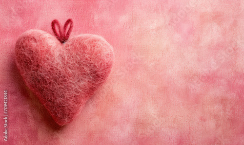 A cute hand made felted love heart on a pink background for Valentine's day