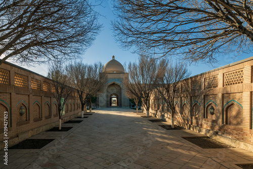View of the Bab-i-Islam Gate and the alley to the Bahauddin Naqshbandi Memorial Complex on a sunny day, Bukhara, Uzbekistan photo