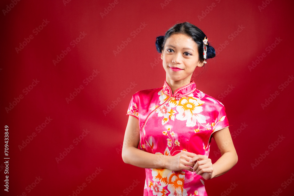 Portrait of an attractive Asian Chinese female wearing cheongsam or qipao on red background for Chinese New Year concept Portrait of an attractive Asian Chinese female wearing cheongsam or qipao on red background for Chinese New Year concept