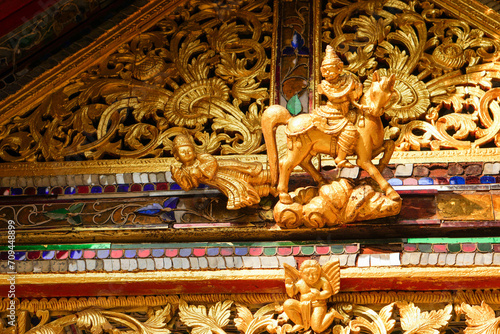 Closeup and crop antique golden carved wood Burmese art on the roof of the Burmese temple chapel in Lampang province, Thailand. photo