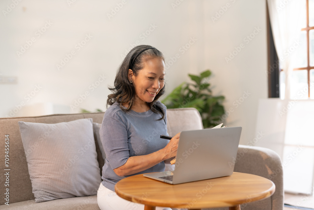 Senior asian woman sitting on sofa using laptop computer, working, chatting, social media internet at home. Senior asian woman sitting on sofa using laptop computer, working, chatting, social media internet at home.