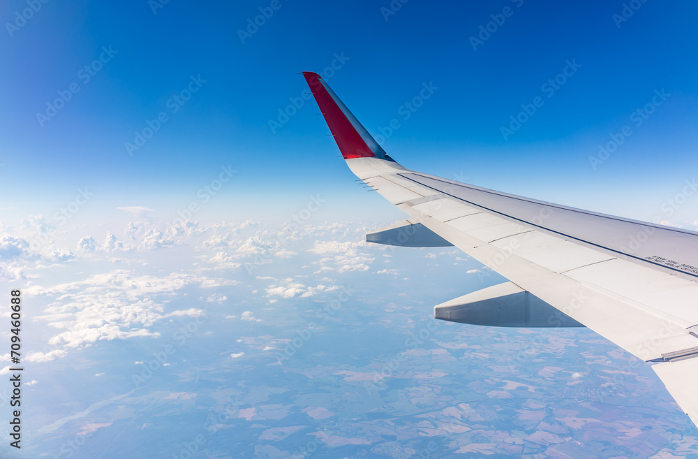 Fototapeta premium View from the airplane window at a beautiful cloudy sky and the airplane wing