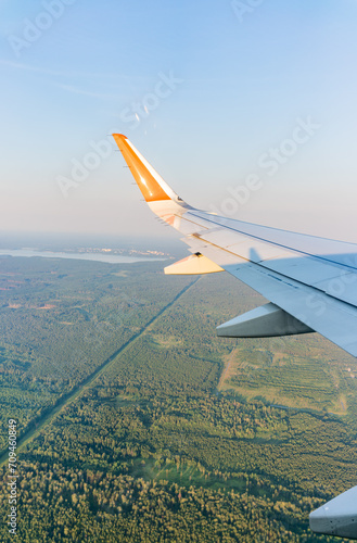 View of airplane wing  blue skies and green land during landing. Airplane window view.