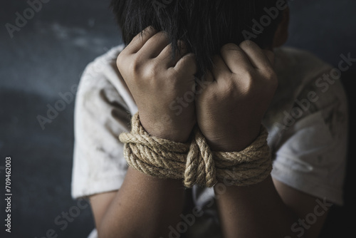 Victim boy with hands tied up with rope in emotional stress and pain,  kidnapped, abused, hostage,  afraid, restricted,  Stop violence against children and trafficking Concept. photo