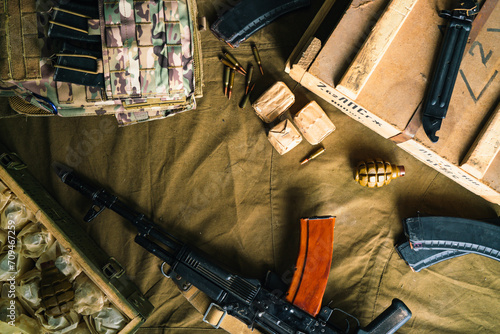 Bild auf Leinwand Military body armor, ammunition, F-1 grenades and a Kalashnikov assault rifle on a brown background, top view