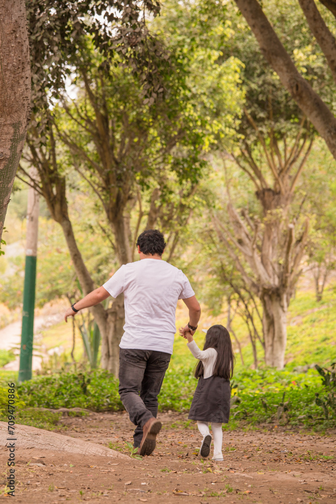 Family members holding hands and walking backwards in a park together family Family members holding hands and walking backwards in a park together family