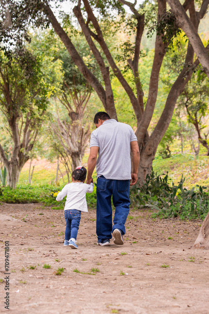Family members holding hands and walking backwards in a park together family Family members holding hands and walking backwards in a park together family