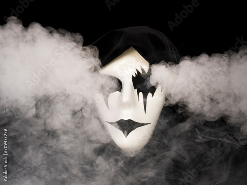 Cloak covered hand made mask with smoke pouring from eyes and background photo