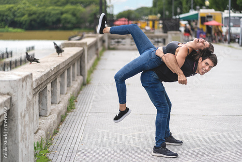 Young playful couple back to back at the park