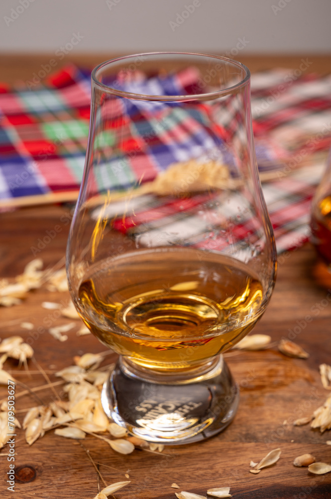 Tasting of different Scotch whiskies strong alcoholic drinks, drum of whiskey and colorful Scotch tartan on background close up Tasting of different Scotch whiskies strong alcoholic drinks, drum of whiskey and colorful Scotch tartan on background close up