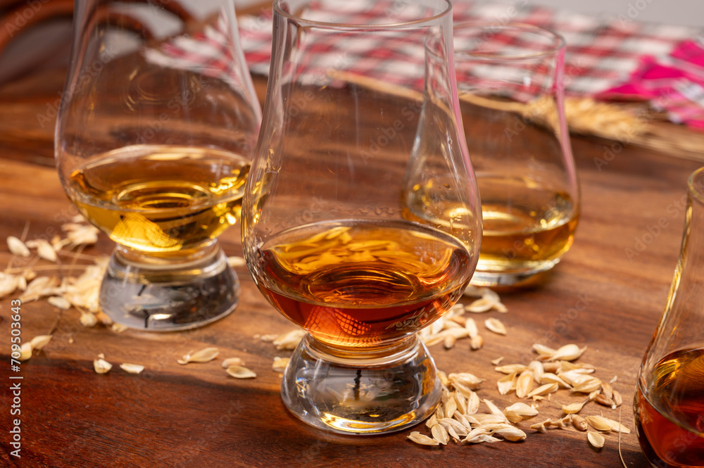Tasting of different Scotch whiskies strong alcoholic drinks, drum of whiskey and colorful Scotch tartan on background close up Tasting of different Scotch whiskies strong alcoholic drinks, drum of whiskey and colorful Scotch tartan on background close up