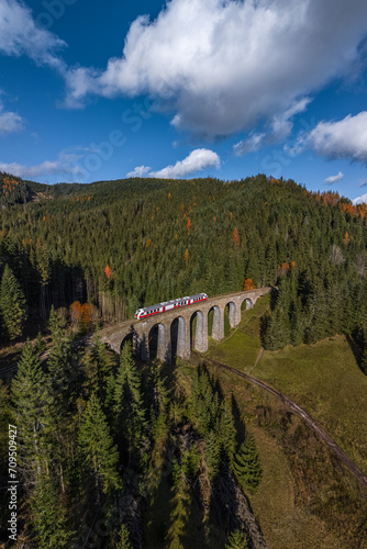 Telgart, Slovakia - Aerial panoramic view of the famous Chmarossky Viaduct in the low Tatras on a sunny autumn day with blue sky and clouds. Regular train is going through the viaduct.