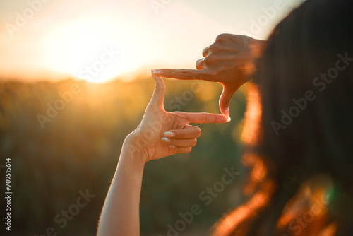 Closeup of woman hands making frame gesture with sunset, Female capturing the sunrise. Future planning concept. photo