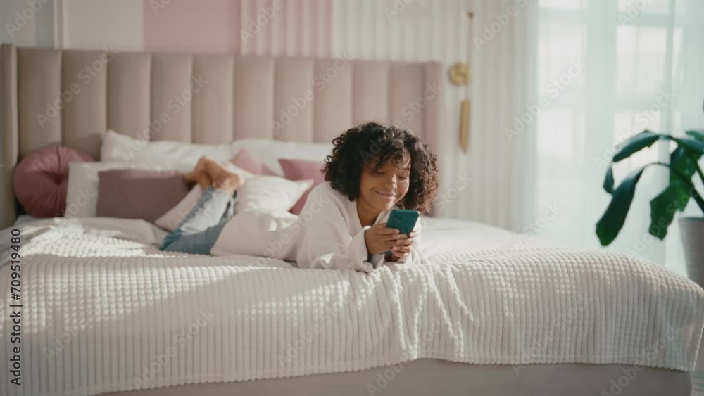 African american woman typing in phone. Contented african american teen girl typing messages in smartphone chatting with friend in bed at home. Smiling teenager enjoying online communication in phone. African american woman typing in phone. Contented african american teen girl typing messages in smartphone chatting with friend in bed at home. Smiling teenager enjoying online communication in phone.