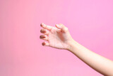 Female hand holding something like a bottle or can isolated on pink background 