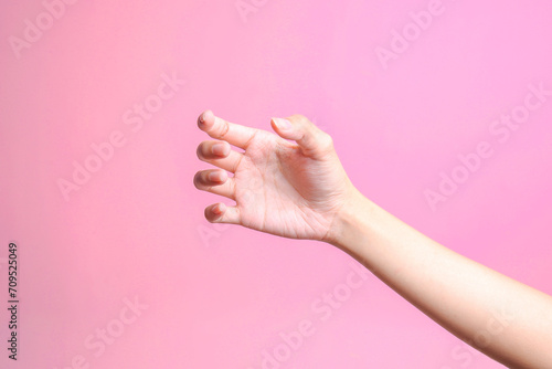 Female hand holding something like a bottle or can isolated on pink background  photo