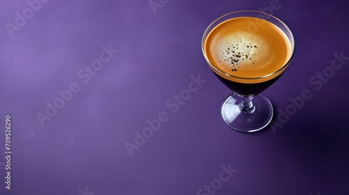  a glass filled with liquid sitting on top of a purple table next to a bottle of liquid on a purple surface.