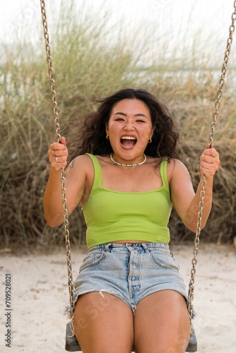 Asian woman sitting on the swings against yellow wall background
