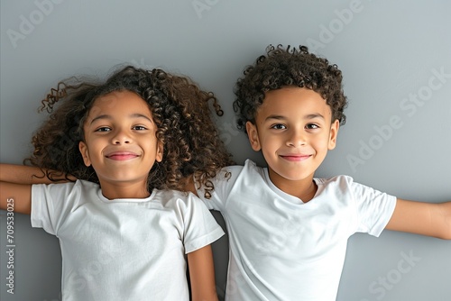 Two little african american girls in white t-shirts on grey background