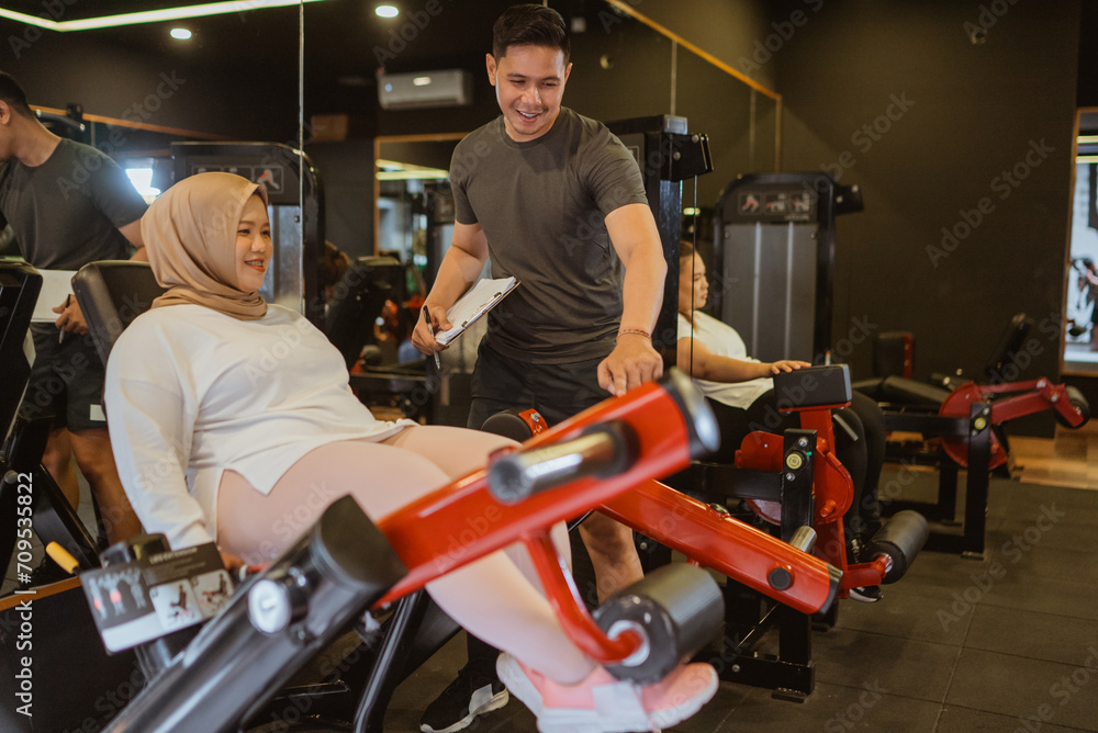 muslim woman working out with personal trainer in gym muslim woman working out with personal trainer in gym