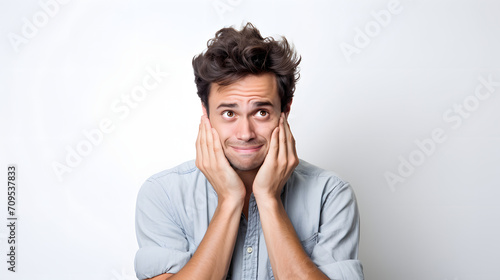 an unexpectedly embarrassed man holding his hands over his face on white background