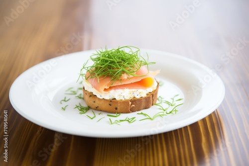 bagel with cream cheese on a white plate, garnished with chives