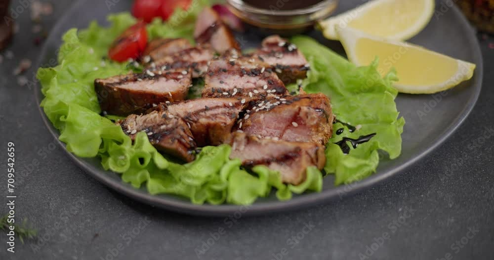 Sliced Fried grilled piece of Organic Tuna Steak on a black ceramic plate with salad Sliced Fried grilled piece of Organic Tuna Steak on a black ceramic plate with salad