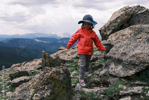 Young girl climbing rocky mountain ridge, enjoying outdoor adventure