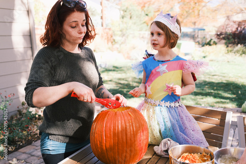 Mother and daughter carving a pumpkin at a Halloween celebration